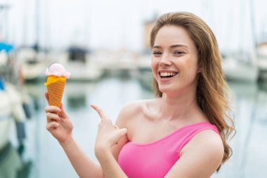 Açık havada kornet dondurmalı genç kızıl saçlı kadın.