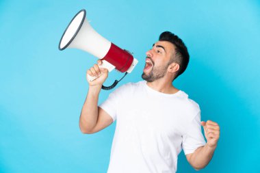 İzole edilmiş mavi arka plan üzerinde beyaz bir adam megafondan bir şey duyurmak için bağırıyor.