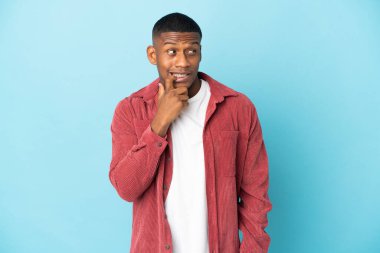 Genç latin adam mavi arka planda izole edilmiş gergin ve korkmuş