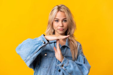 Young Russian woman isolated on yellow background making time out gesture