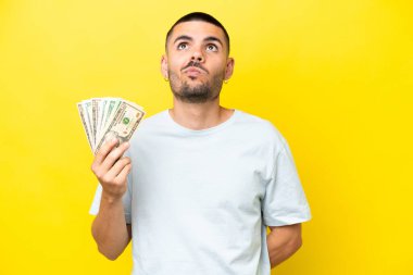 Kafkasyalı genç bir adam çok para alıyor. Sarı arka planda izole edilmiş ve araştırılıyor.