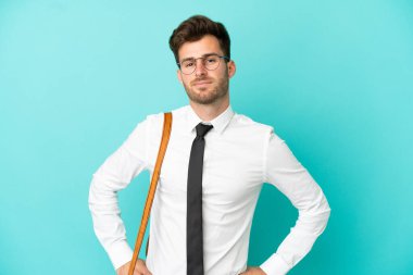 İş adamı soyutlanmış arka planda kolları kalçasında ve gülümseyerek poz veriyor.