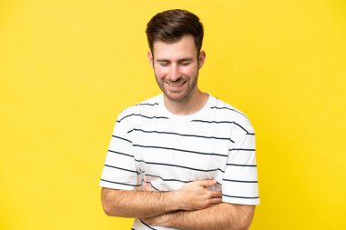 Sarı arka planda izole edilmiş genç beyaz adam çok gülümsüyor.