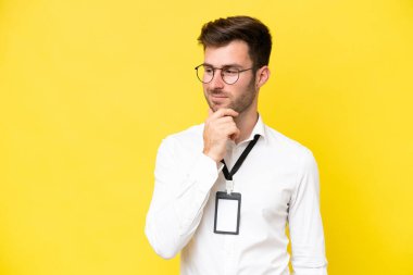 Sarı arka planda izole edilmiş kimliği olan beyaz bir genç. Yan tarafa bakıyor ve gülümsüyor.