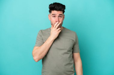 Mavi arka planda izole edilmiş genç beyaz adam sağa bakarken şaşırdı ve şok oldu.