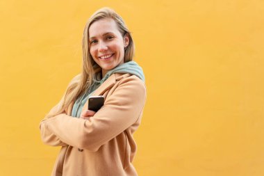 Dışarıda cep telefonu tutan ve kolları bağlı genç sarışın bir kadın.