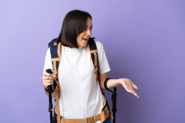 Sırt çantalı ve sırıkla mavi arka planda izole edilmiş beyaz bir kadın.
