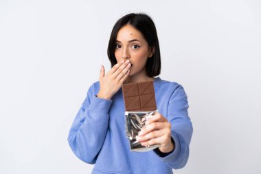 Beyaz arka planda izole edilmiş beyaz bir kadın çikolata tableti alıyor ve şaşırıyor.