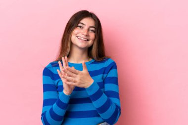 Pembe arka planda izole edilmiş genç beyaz kadın bir konferanstan sonra alkışlıyor.