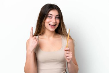 Young caucasian woman brushing teeth isolated on white background pointing up a great idea