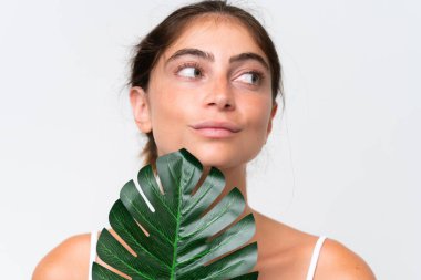 Young Pretty caucasian woman isolated on white background holding a palm leaf. Close up portrait