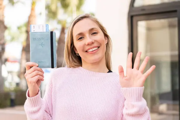 Sarışın Bir Kadın Elinde Pasaport Elinde Mutlu Bir Ifadeyle Selamlıyor — Stok fotoğraf