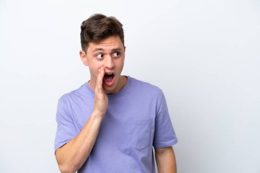 Genç, yakışıklı Brezilyalı bir adam beyaz arka planda izole edilmiş. Yan tarafa bakarken sürpriz bir jest yapıyor.