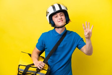 Sırt çantalı genç Brezilyalı adam sarı arka planda izole edilmiş mutlu ve parmakları olan dört kişi sayıyor.