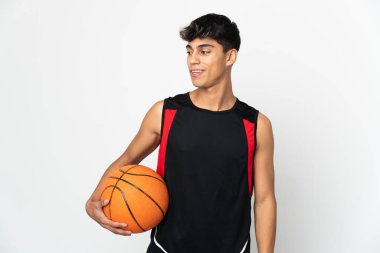İzole edilmiş beyaz arka planda basketbol oynayan genç bir adam.