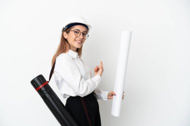 Miğferli ve elinde beyaz arka planda izole edilmiş planları olan genç bir mimar kadın.