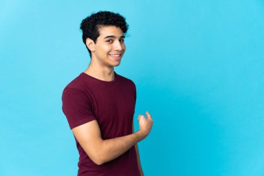 Genç Venezuelalı adam mavi arka planda izole edilmiş.