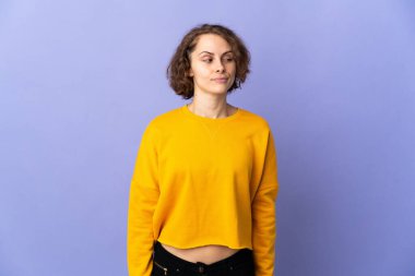 Young English woman isolated on purple background having doubts while looking side