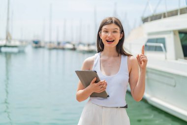 Genç, güzel Ukraynalı bir kadın elinde tabletle dışarıda harika bir fikri işaret ediyor.