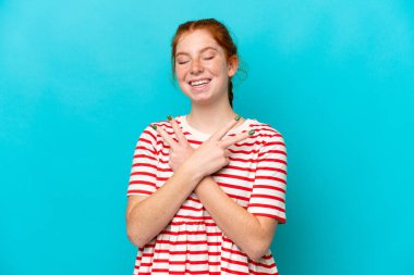 Mavi arka planda izole edilmiş genç, kırmızı bir kadın gülümsüyor ve zafer işareti gösteriyor.