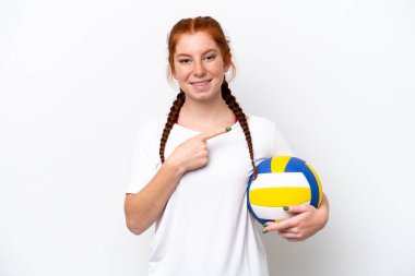 Beyaz arka planda izole edilmiş voleybol oynayan beyaz tenli genç beyaz kadın bir ürünü sunmak için kenarı işaret ediyor.