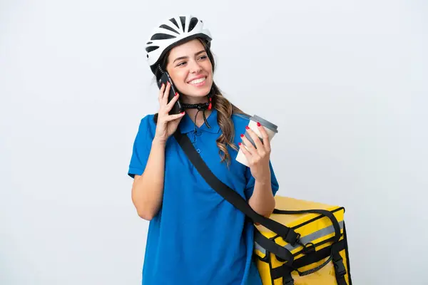 Young delivery woman with thermal backpack isolated on white background holding coffee to take away and a mobile