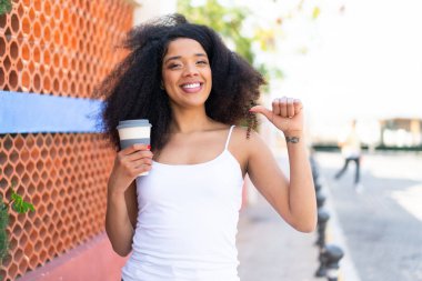 Genç Afrikalı Amerikalı kadın açık havada kahvesini yudumlarken gururlu ve kendini beğenmiş.