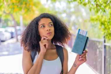 Genç Afrikalı Amerikalı bir kadın elinde pasaport ve şöyle düşünüyor: