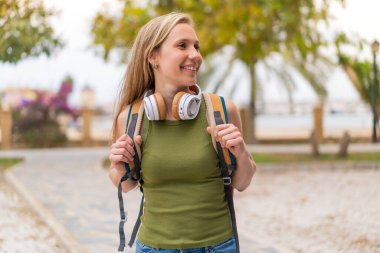 Genç sarışın kadın açık havada mutlu bir ifade sergiliyor.