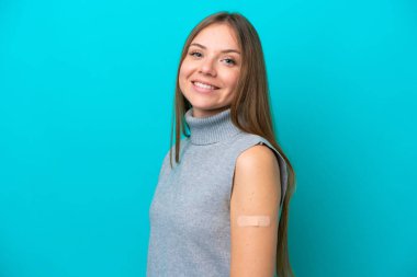 Mavi arka planda izole edilmiş yara bandı takan Litvanyalı genç bir kadın çok gülümsüyor.