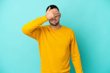 Genç, yakışıklı, beyaz bir adam mavi arka planda tek başına, gözleri elleriyle kapatıyor. Bir şey görmek istemiyorum.