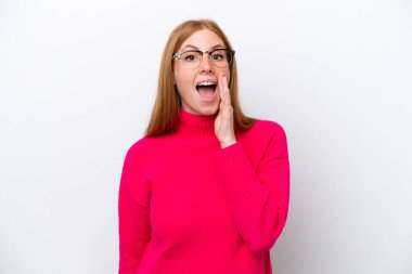 Genç kızıl saçlı kadın beyaz arka planda izole edilmiş, şaşırmış ve şok olmuş bir yüz ifadesi var.