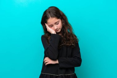 Mavi arka planda başağrısı olan küçük bir kız.