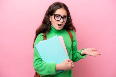 Yüzünde şok ifadesi olan pembe arka planda izole edilmiş küçük öğrenci kız.