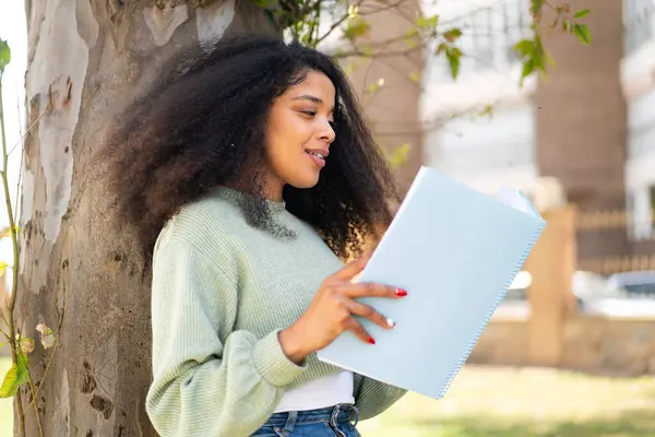 Genç Afrikalı Amerikalı bir kadın elinde bir defter tutuyor.