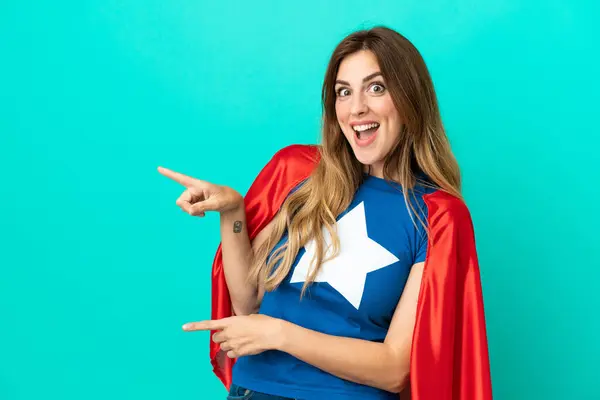 Super Hero Caucasian Woman Isolated Blue Background Surprised Pointing Side — Foto Stock