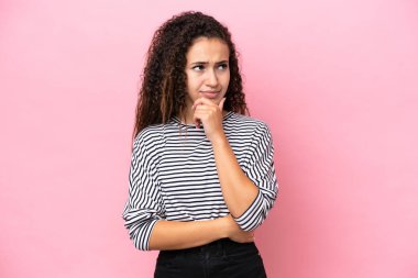 Genç İspanyol kadın pembe arka planda izole edilmiş bir şekilde bakarken bir fikir düşünüyor.