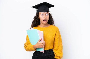 Arap üniversitesi mezunu kadın elinde kitaplarla beyaz arka planda izole bir şekilde yukarı bakıyor ve şaşırmış bir ifadeyle