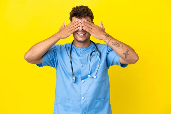 手で目を覆う黄色い背景に隔離された若い外科医の医者男性 — ストック写真