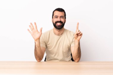 Masada sakallı beyaz adam parmaklarıyla altışar sayıyor..