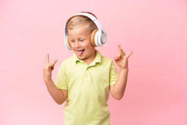 Küçük Rus çocuk pembe arka planda izole edilmiş müzik ve dans dinliyor.