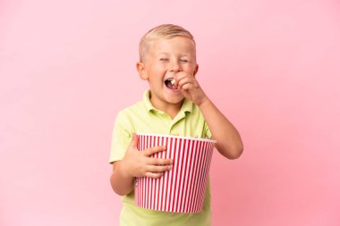 Küçük Rus çocuk izole bir arka planda büyük bir kasede patlamış mısır yiyor.