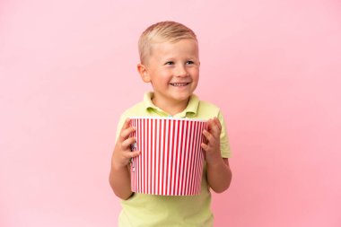 Küçük Rus çocuk izole bir arka planda büyük bir kasede patlamış mısır yiyor.