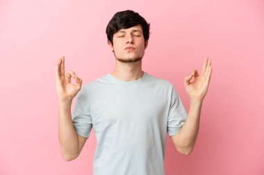 Zen pozisyonunda pembe arka planda izole edilmiş genç bir Rus.