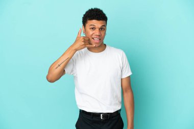 Genç Afrikalı Amerikalı adam mavi arka planda izole edilmiş bir şekilde telefon jesti yapıyor. Bana geri dönüş işareti ver.