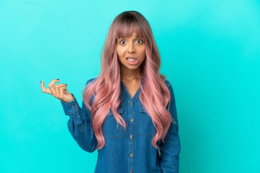 Mavi arka planda pembe saçlı melez bir kadın şüpheli hareketler yapıyor.