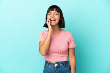 Mavi arka planda izole edilmiş genç melez bir kadın ağzı açık bağırıyor.