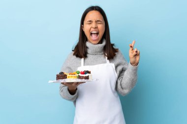 Pasta şefi izole edilmiş mavi arkaplanda büyük bir pasta tutuyor..