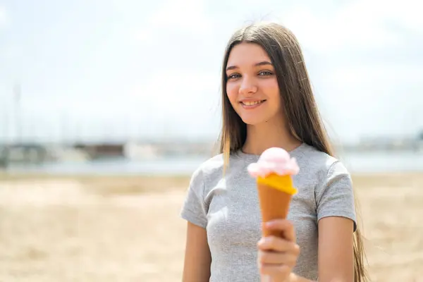 Teenager girl with a cornet ice cream at outdoors with happy expression