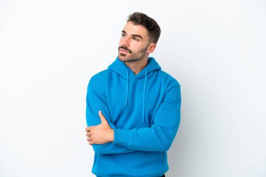Beyaz arka planda izole edilmiş genç beyaz adam yan tarafa bakıyor.